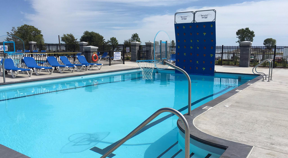 Outdoor leisure pool with a climbing wall and basketball hoop at Quinte's Isle Campark